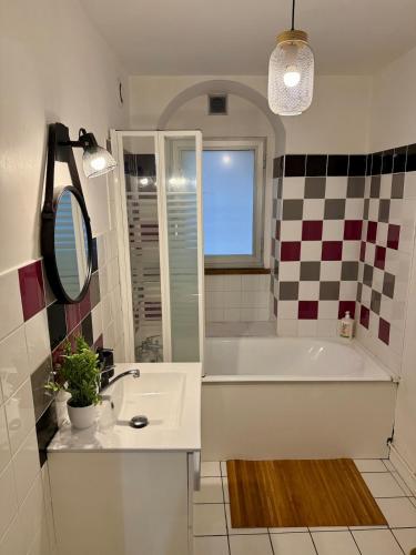 a bathroom with a tub and a sink and a mirror at Le Petit Bohème - WiFi - Hyper-Centre in Bourges
