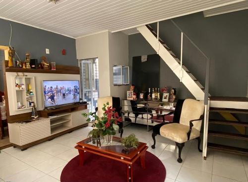 a living room with a tv and a table and a couch at Suite Cop Belém in Belém