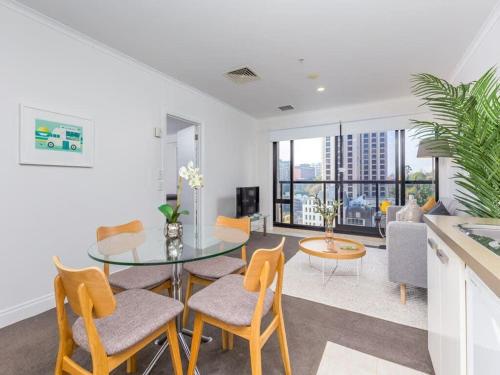 a dining room with a glass table and chairs at Cozy City Apt with Pool, Gym & View by Zodiak Stays in Auckland