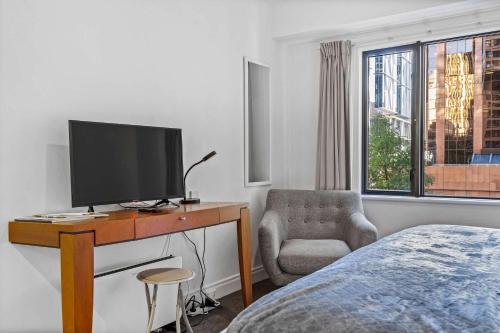 1 dormitorio con TV, silla y cama en Cozy Room with King Bed, Gym and Pool Zodiak Stays, en Auckland