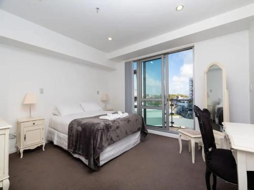 a bedroom with a bed and a desk and a window at Spacious Home with Balcony Parking Zodiak Stays in Auckland