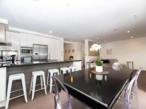 a kitchen and dining room with a black table and white chairs at Spacious Home with Balcony Parking Zodiak Stays in Auckland