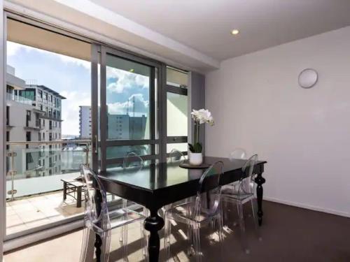 a dining room with a table and chairs and a large window at Spacious Home with Balcony Parking Zodiak Stays in Auckland