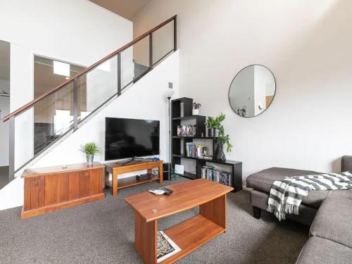 a living room with a couch and a television at Roomy Loft 2 Bedroom with Free Parking Zodiak Stays in Auckland