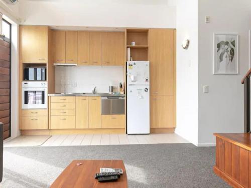 a kitchen with wooden cabinets and a white refrigerator at Roomy Loft 2 Bedroom with Free Parking Zodiak Stays in Auckland