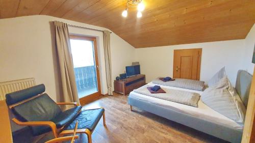 a living room with a bed and a chair at Chiemsee-Ferienhaus Schlegel in Breitbrunn am Chiemsee