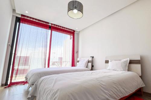 two beds in a bedroom with a large window at Serenity - Appart Piscine - 4-5p in Agadir