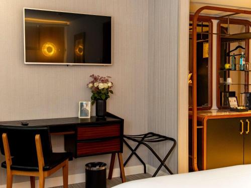 a hotel room with a desk and a television at MUZE Hotel Dusseldorf - Handwritten Collection in Düsseldorf