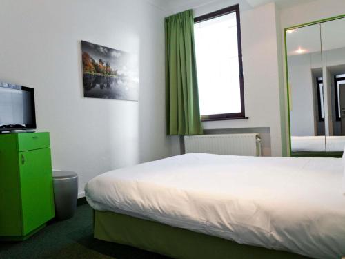 a hotel room with a bed and a green window at Hotel Siru Brussels in Brussels