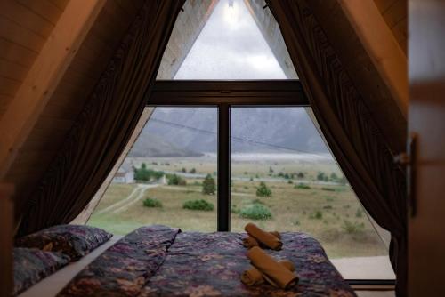 a bedroom with a large window looking out at a field at Blidinje Lake House in Blidinje