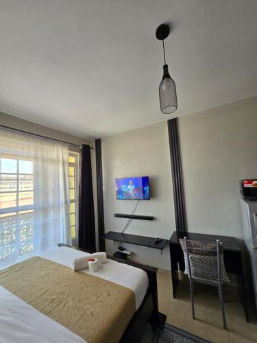 a hotel room with a bed and a desk and a window at Affordable Luxury Ruaka in Ruaka
