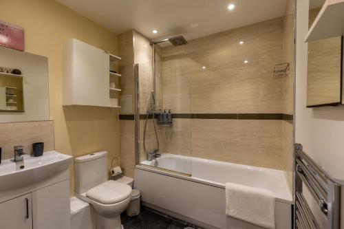a bathroom with a tub and a toilet and a sink at Central Luton Ground Floor Flat Sleeps 4 in Luton