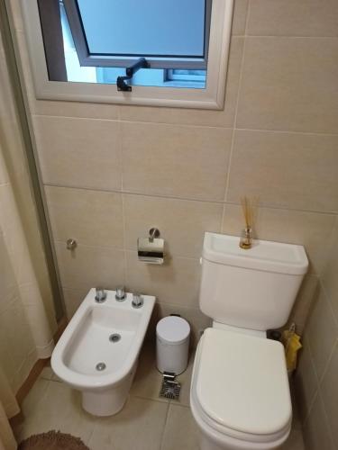 un bagno con un water, un lavandino e una finestra di Temporary Rental a Chivilcoy