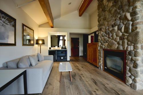 a living room with a couch and a stone fireplace at Gravity Haus Big Sky in Big Sky