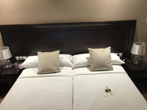a large white bed with a black headboard and pillows at Hotel Calzada in Arcos