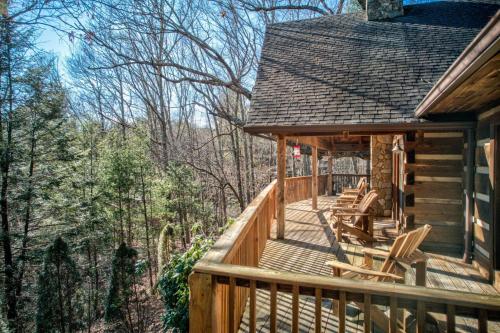 a cabin with chairs on a deck in the woods at Fox's Lair in Sugar Grove