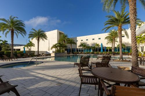 a pool with chairs and a table and palm trees at The Luxury spot 2 min to DOWNTOWN 5 min to The beach in Fort Myers