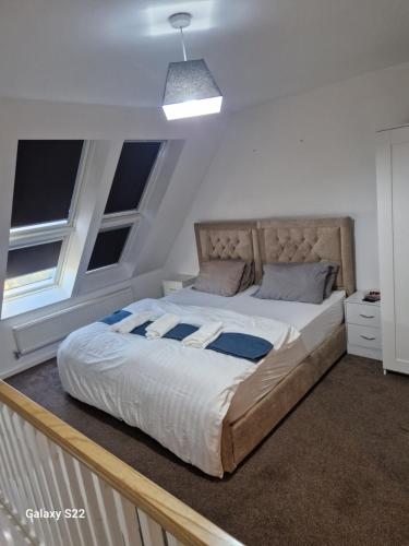 a large bed in a room with two windows at Blue Haven 2 in Manchester