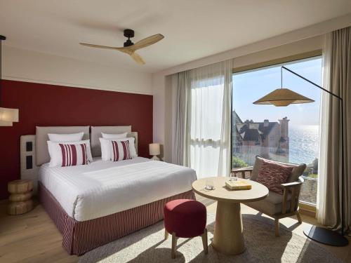 a hotel room with a bed and a large window at Le Talaia Hôtel & Spa Biarritz - MGallery Collection in Biarritz