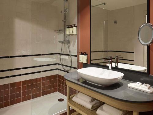 a bathroom with a sink and a shower and a tub at Le Talaia Hôtel & Spa Biarritz - MGallery Collection in Biarritz