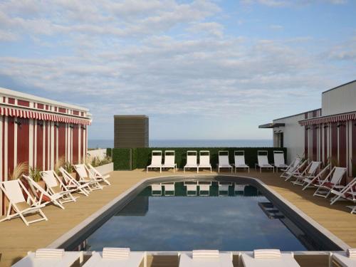 a swimming pool on the roof of a building with chairs at Le Talaia Hôtel & Spa Biarritz - MGallery Collection in Biarritz