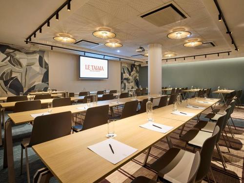 a conference room with tables and chairs and a screen at Le Talaia Hôtel & Spa Biarritz - MGallery Collection in Biarritz