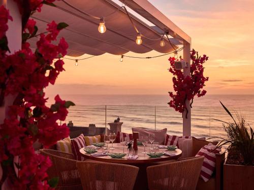 a table on the beach with a view of the ocean at Le Talaia Hôtel & Spa Biarritz - MGallery Collection in Biarritz
