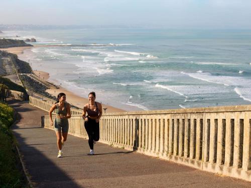 two women running on a walkway near the beach at Le Talaia Hôtel & Spa Biarritz - MGallery Collection in Biarritz