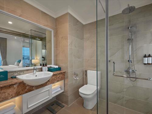 a bathroom with a toilet and a sink and a shower at Mercure Nha Trang Beach in Nha Trang