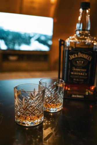 two glasses sitting on a table with a bottle of whiskey at Blidinje Lake House in Blidinje