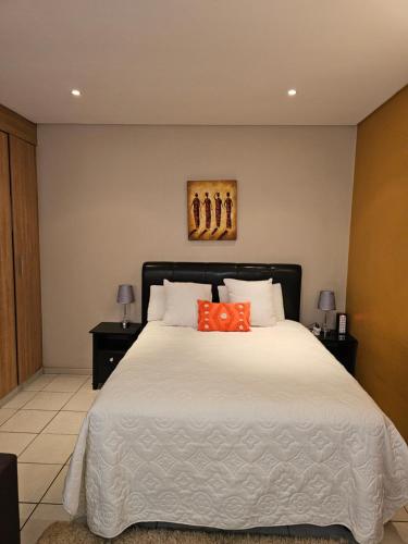 a bedroom with a large white bed with an orange pillow at The Orange Corner II in Johannesburg
