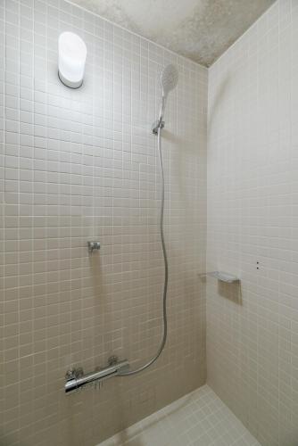 a shower in a tiled bathroom with a shower head at One Floor Designed by Architect Tadao Ando in Ikuma