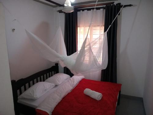um quarto com uma cama vermelha e uma rede mosquiteira em The Truenorth apartments chitiri em Ukunda