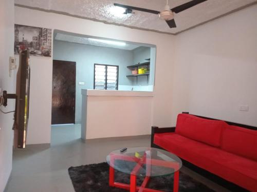 uma sala de estar com um sofá vermelho e uma mesa em The Truenorth apartments chitiri em Ukunda