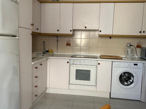 a kitchen with white cabinets and a washing machine at Sella in Arriondas
