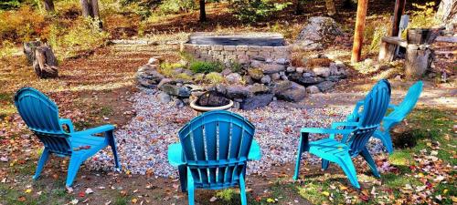 three blue chairs and a fire pit in a yard at Winter Lore in Mendon