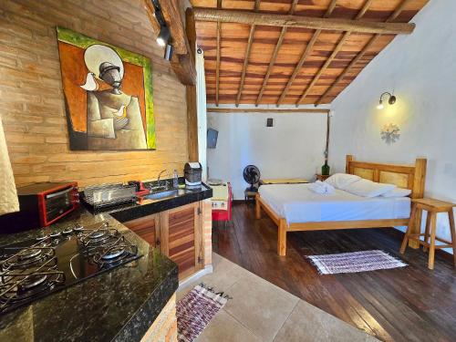 a bedroom with a bed and a kitchen with a stove at Chalezinho Mata Virgem - perto do centro e cachoeiras, cozinha completa e churrasqueira in Carrancas
