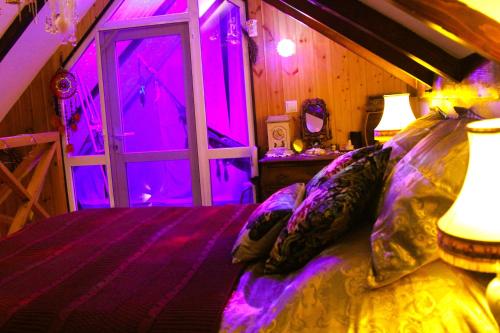 a bedroom with purple lighting and a bed with pillows at budabu in Sighnaghi