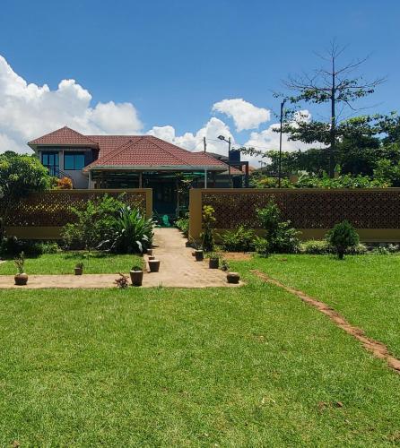 a house with a walkway in front of a yard at Gipir & Labango Ventures in Entebbe