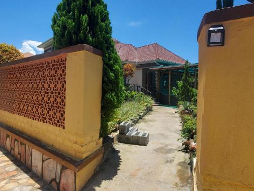 a house with a brick wall next to a sidewalk at Gipir & Labango Ventures in Entebbe