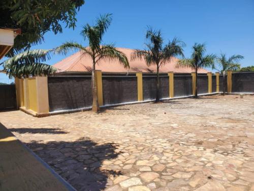 a fence with palm trees in a yard at Gipir & Labango Ventures in Entebbe