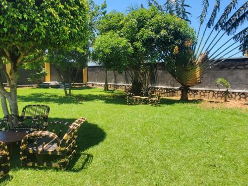 a yard with chairs and a table and trees at Gipir & Labango Ventures in Entebbe