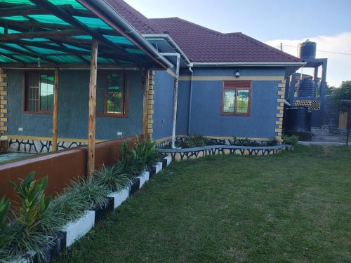 a blue house with benches in a yard at Gipir & Labango Ventures in Entebbe