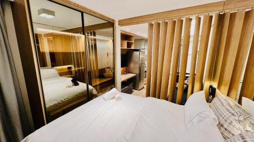 een slaapkamer met een wit bed en een spiegel bij Flat Luxo Jardins com Piscina, Vaga e serviços in Sao Paulo