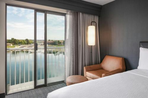 a hotel room with a bed and a chair and a window at Courtyard Richland Columbia Point in Richland