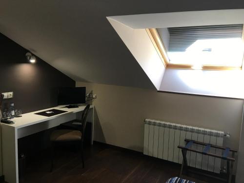 an attic room with a desk and a window at Hotel Calzada in Arcos