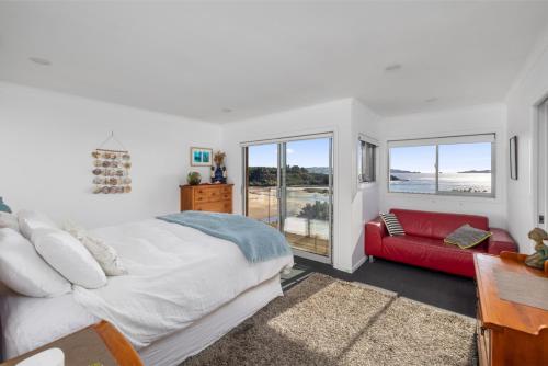 Un dormitorio con una cama grande y un sofá rojo. en Coastal Serenity - Tapuaetahi Beach Escape, en Purerua
