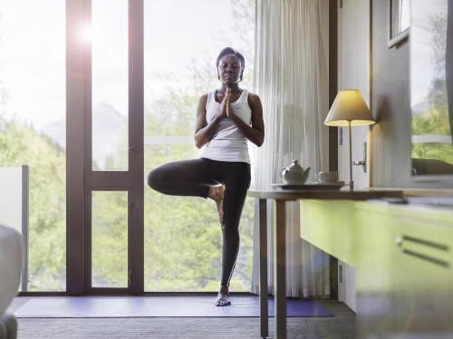 a woman doing a yoga pose in front of a window at Novotel Queenstown Lakeside in Queenstown