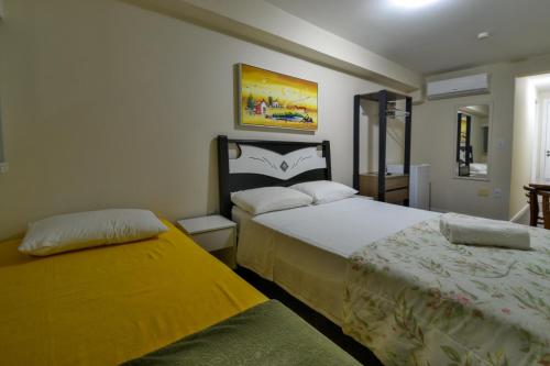 a bedroom with two beds and a yellow blanket at Hostel Toca da Moréia Bombinhas in Bombinhas