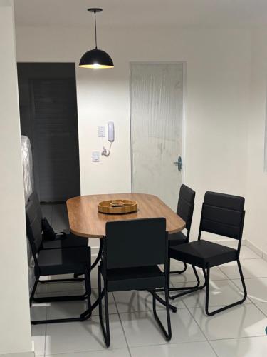 a dining room with a wooden table and black chairs at Casa Delta 187 in Parnaíba